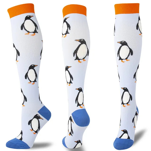 A set of multi-color compression socks featuring penguin designs in black, white, and orange on a white background.