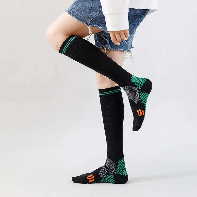 Calcetines de compresión médicos negros con dedos estampados en verde y naranja, puestos en la pierna de una persona.