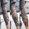 Close-up of a person wearing dark gray UV protection tattoo arm sleeves featuring intricate tribal and animal designs on thei