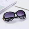 Black vintage oversized retro sunglasses resting on a white surface next to a book.
