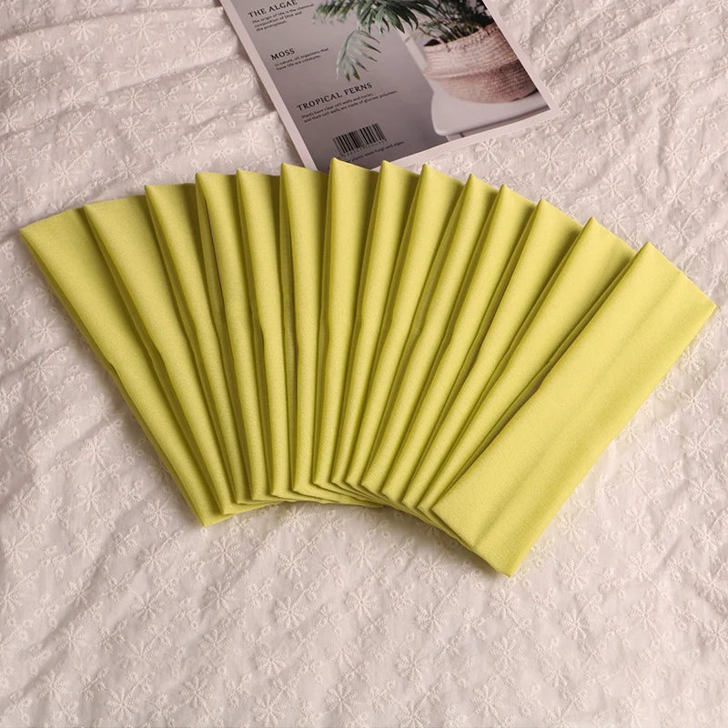 A fan of bright lime green elastic headbands folded and displayed on a white textured surface.