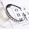 A black headband adorned with double layers of pearls and rhinestones, displayed on white paper.