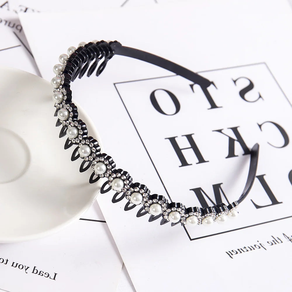 A black headband adorned with double layers of pearls and rhinestones, displayed on white paper.