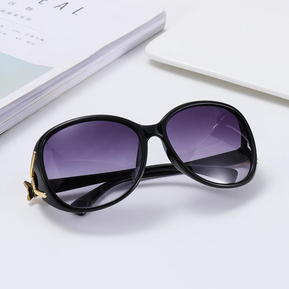 Black vintage oversized retro sunglasses resting on a white surface next to a book.