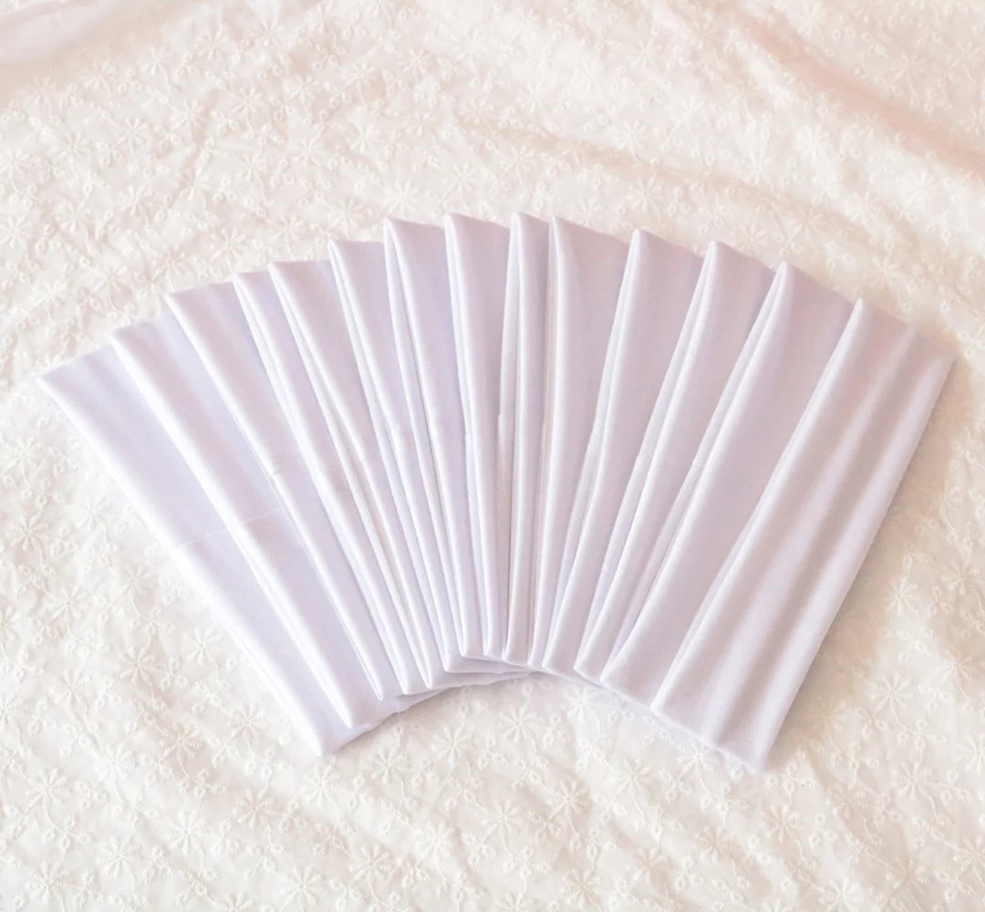 A fan of white elastic headbands folded and displayed on a white textured surface.