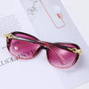 Pink tinted vintage oversized retro sunglasses resting on a white paper with a lightbulb.