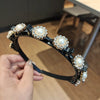 A black headband adorned with multiple clusters of white pearls and clear rhinestones.