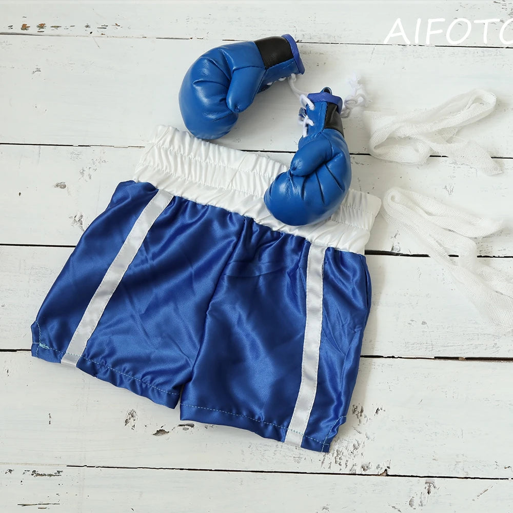 Llaves de guantes de boxeo azules y pantalones cortos deportivos a juego en una superficie de madera blanca.