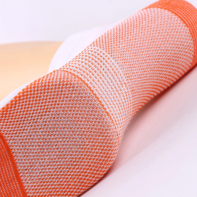 Gros plan de chaussettes de compression en fibre de cuivre orange et blanc, roulées ou exposées.