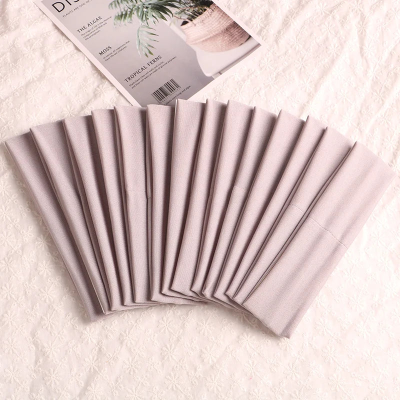 A fan of multi-use elastic headbands for sports and hair in a soft pink color.