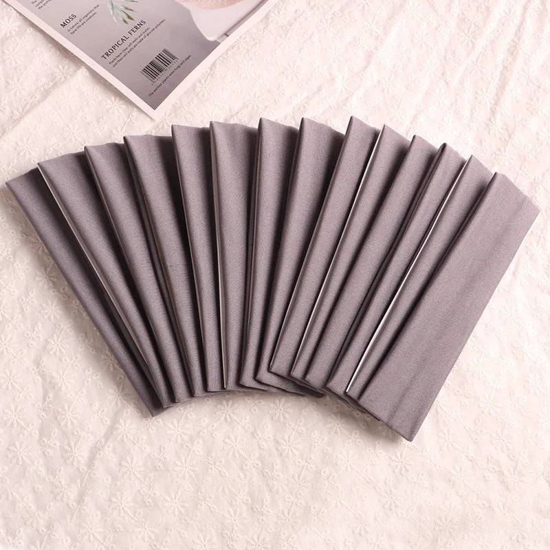A fan of gray elastic headbands rolled into a neat stack on a white fabric background.