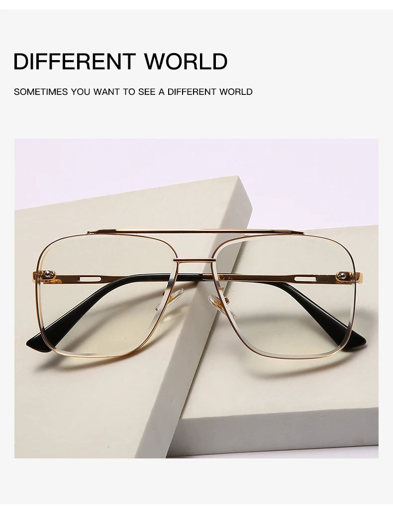 Un par de gafas con montura de metal dorado y lentes transparentes sobre una superficie blanca.