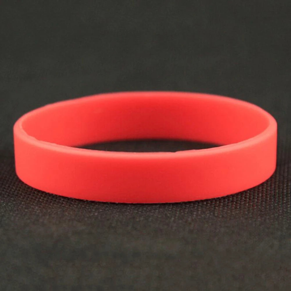A bright red silicone elastic wristband lying on a dark surface.