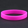 A bright pink silicone elastic wristband lying flat on a dark surface.