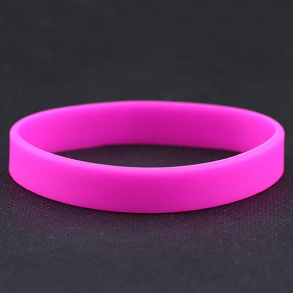 A bright pink silicone elastic wristband lying flat on a dark surface.