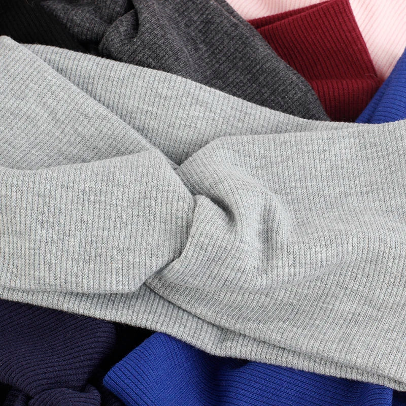 Una pila de bandas para la cabeza de algodón tejido en varios colores, incluyendo gris, granate y azul.