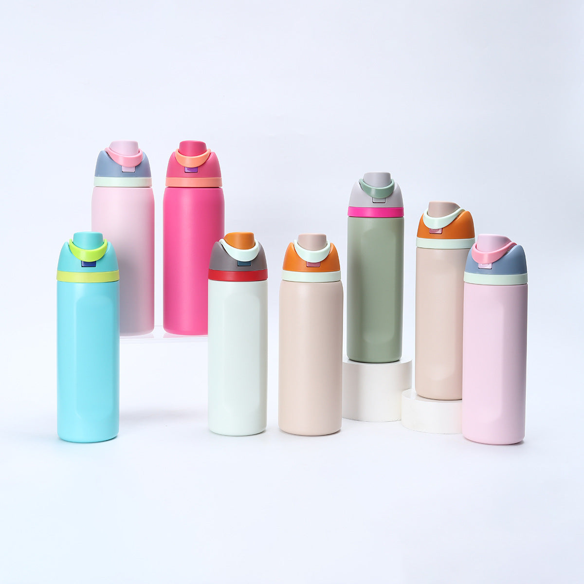 A collection of pink, green, and blue insulated stainless steel thermos mugs with straws arranged in a row and on a stand.