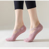Un par de calcetines de punto rosa para yoga y pilates puestos descalzos contra un fondo claro.