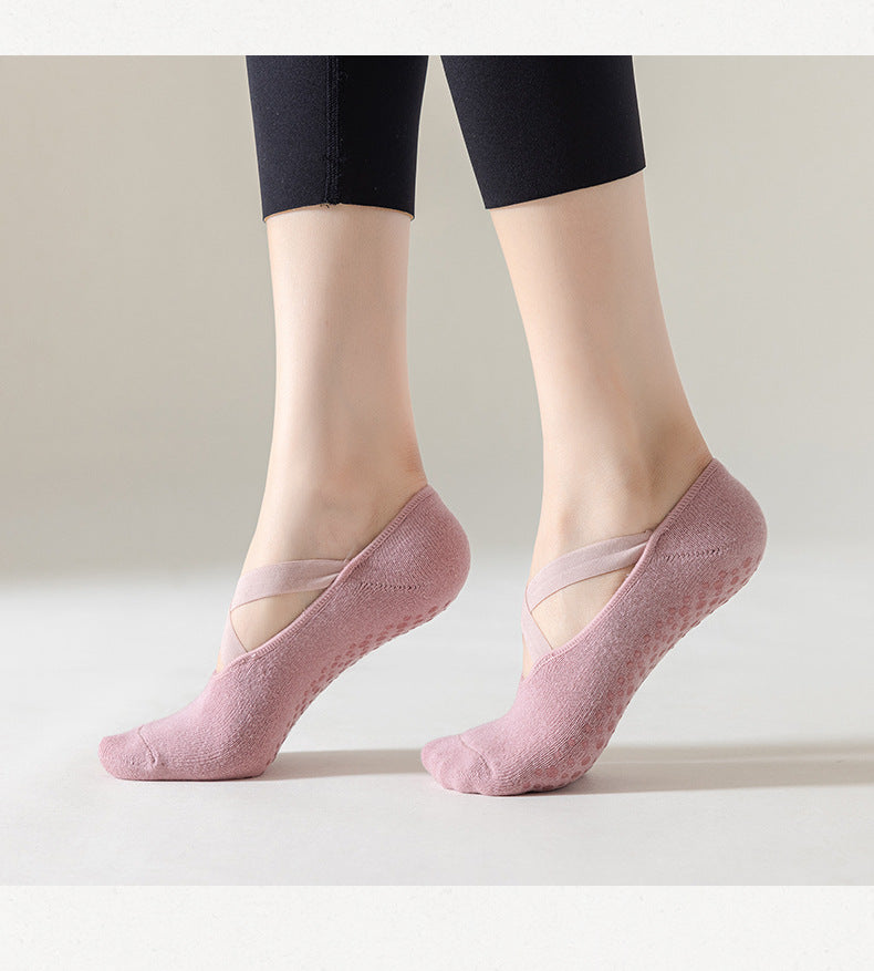 Un par de calcetines de punto rosa para yoga y pilates puestos descalzos contra un fondo claro.