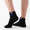 A pair of black ankle socks with a blue and white embroidered logo on the cuff.