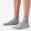 A pair of grey ankle socks with a red and blue logo on the cuff