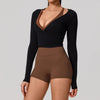 A woman wearing a black long sleeve top with a brown V-neck and matching high-waisted bottoms.