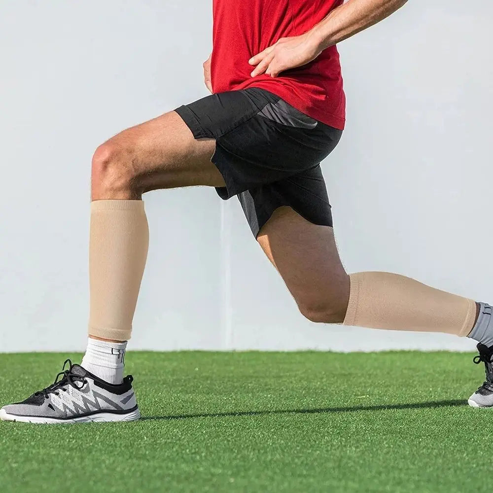 A person wearing red a shirt and black shorts is exercising while wearing tan calf compression sleeves.