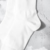 A close-up of a white crew sock with subtle vertical ribbing and a small mark on the ankle area.