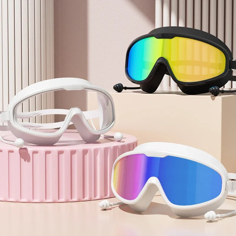 Exhibición de varias gafas de natación antiempañante con lentes blancas y multicolor sobre una superficie rosa claro.