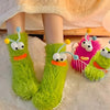 Pair of bright lime green knit socks with cartoon faces resting on a white fluffy surface.