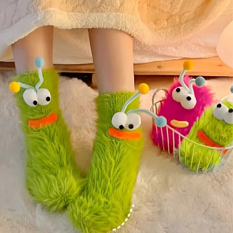Pair of bright lime green knit socks with cartoon faces resting on a white fluffy surface.