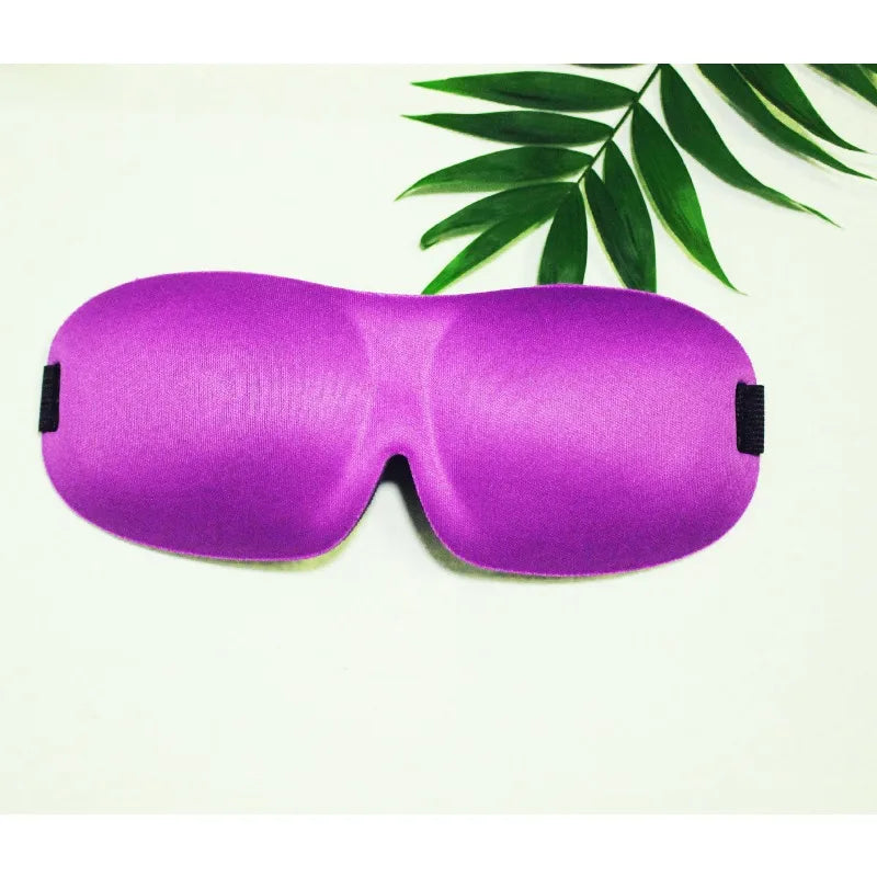 Purple memory foam sleep mask lying on a white surface with green leaves in the background.