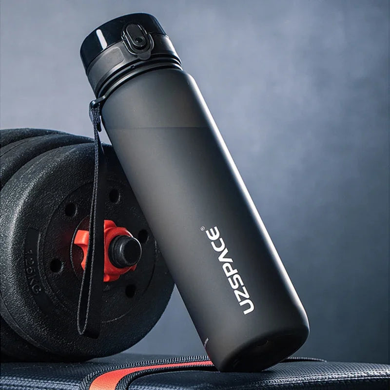 Schwarze wiederverwendbare Sportflasche mit Trageleine neben einem schwarzen Trainingsrad.