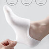 A close-up of a white men's invisible silicone no-show sock being held on a foot.