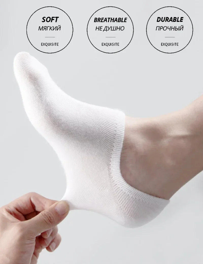 A close-up of a white men's invisible silicone no-show sock being held on a foot.