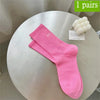 Ein Paar leuchtend pinker, atmungsaktiver, rutschfester Yoga- und Fitnesssocken auf einem weißen Tisch.