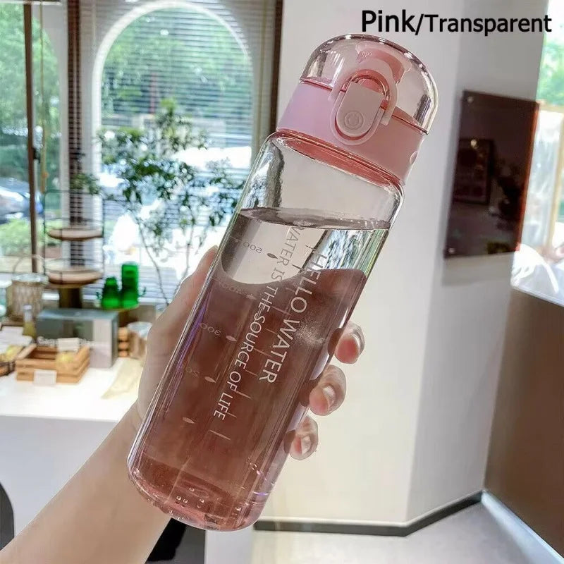 Eine Hand hält eine rosa transparente Sportflasche mit Wasser in einem hellen Innenraum.