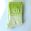 A light lime green knitted sock with a subtle striped pattern and a logo on the toe area.