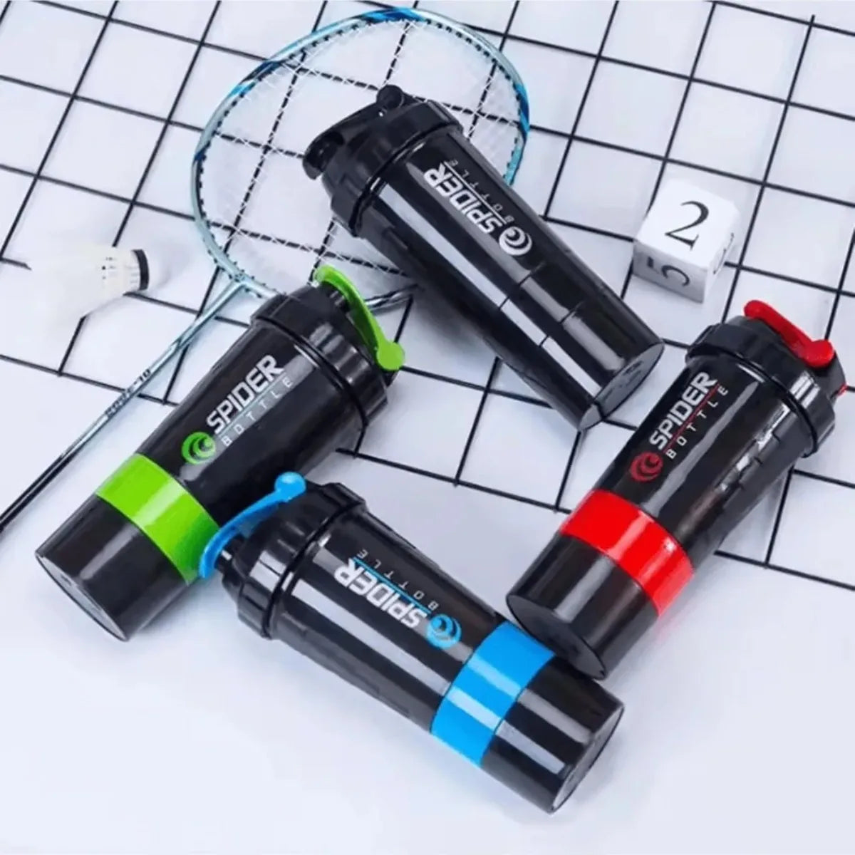Black and green leak-proof protein shaker bottles with pill trays arranged on a grid background.