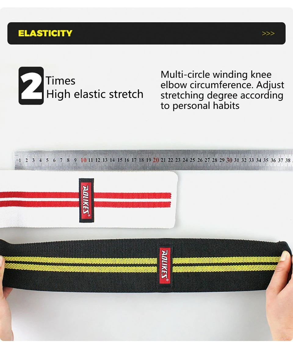 Black elastic knee wraps with yellow stripes shown next to a ruler and a hand.
