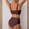 Un mannequin portant un maillot de bain deux pièces froncé marron taille haute avec fines bretelles.