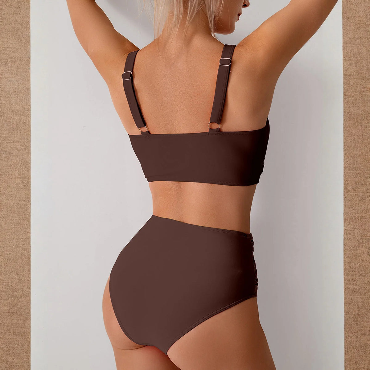 Un mannequin portant un maillot de bain deux pièces froncé marron taille haute avec fines bretelles.