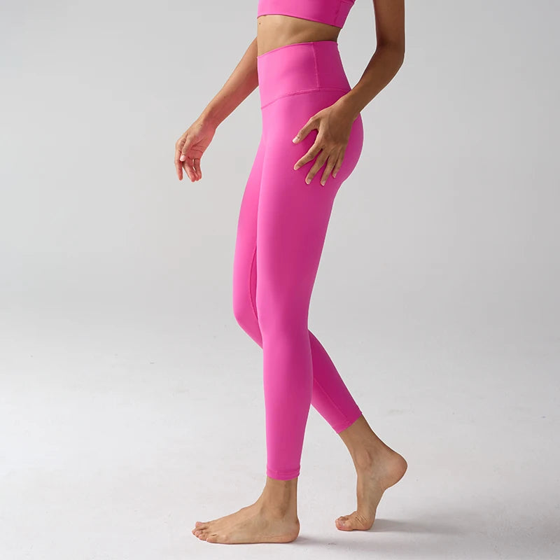 Un mannequin portant des leggings de performance rose vif à taille haute, debout sur un fond gris clair.