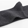 Gros plan d'un chaussette de tricot gris foncé pliée et présentée sur un fond blanc.