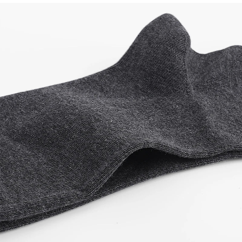 Gros plan d'un chaussette de tricot gris foncé pliée et présentée sur un fond blanc.