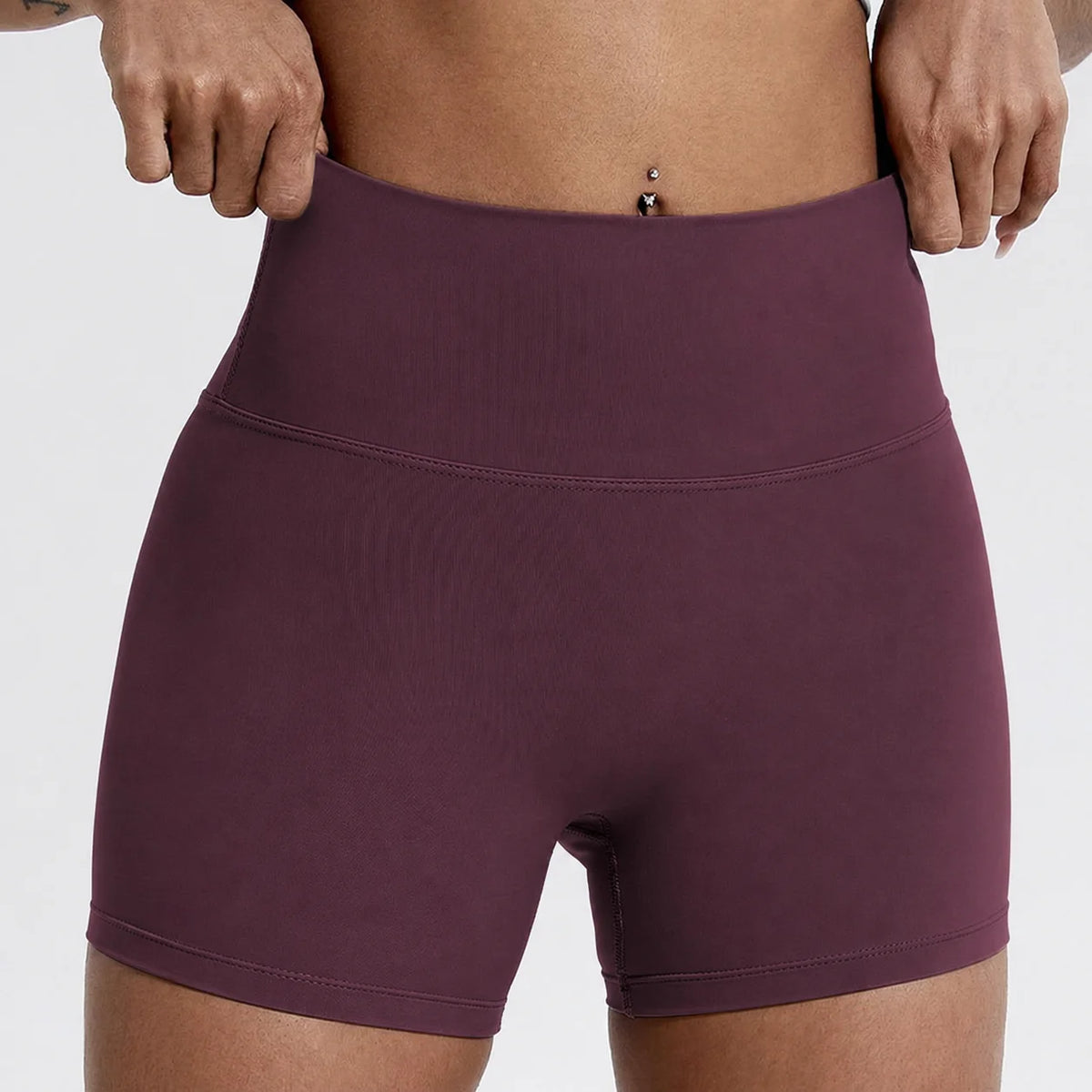 Un mannequin porte un short de yoga et de sport à taille haute, de couleur prune foncé.