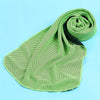 A lime green microfiber cooling towel is rolled up on a light blue surface.