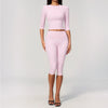 A woman models a light pink yoga and fitness leggings set consisting of a long-sleeved top and matching leggings.