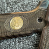 Close-up of a wooden firearm grip with diamond pattern grips and a brass medallion.