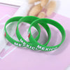 Green silicone wristbands with Mexico text displayed on a pink background.